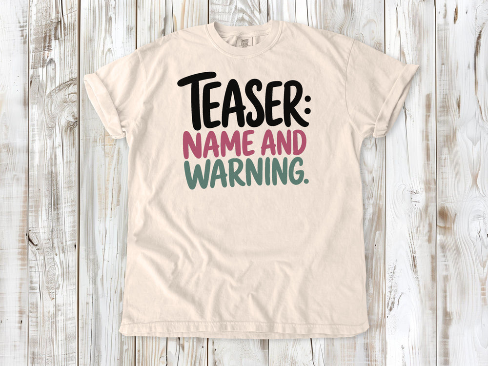 Ivory garment-dyed tee with Teaser Name and Warning Pilates exercise graphic.