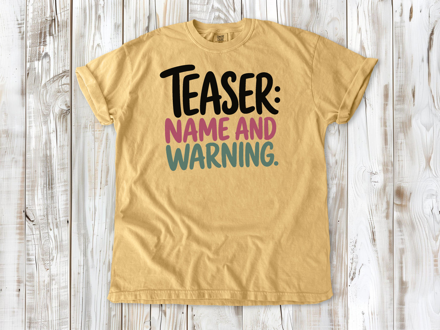 Mustard garment-dyed tee with Teaser Name and Warning Pilates exercise graphic.