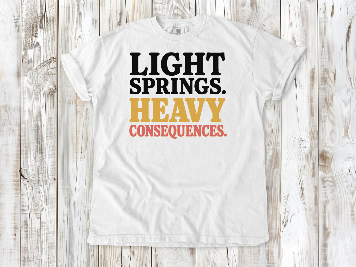 White garment-dyed tee with Light Springs Heavy Consequences reformer Pilates graphic.