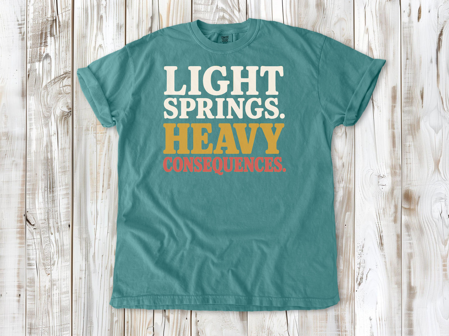 Seafoam garment-dyed tee with Light Springs Heavy Consequences reformer Pilates graphic.
