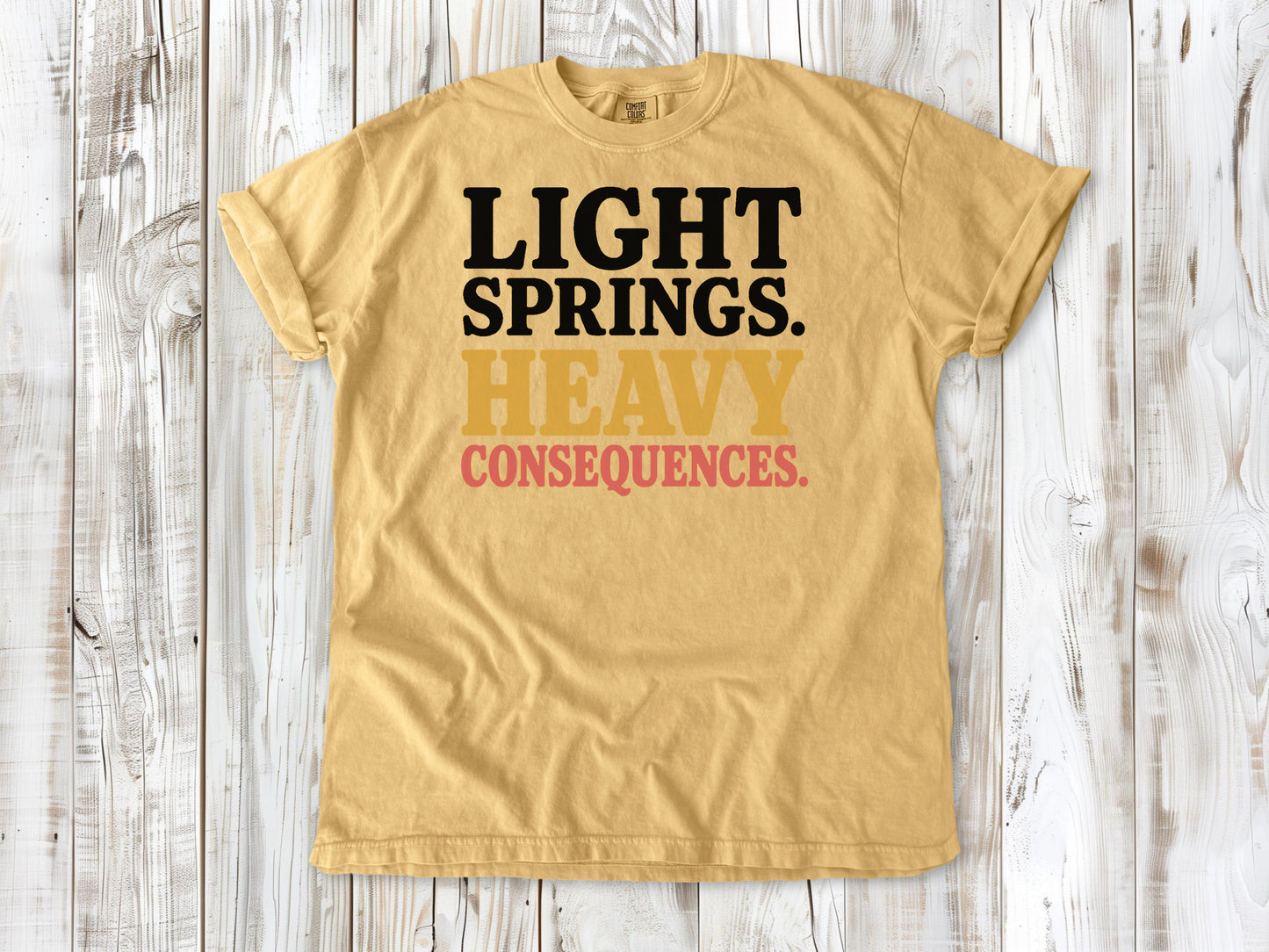 Mustard garment-dyed tee with Light Springs Heavy Consequences reformer Pilates graphic.