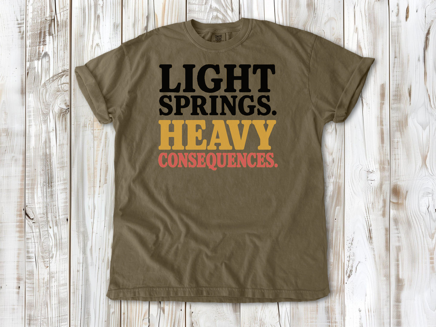 Khaki garment-dyed tee with Light Springs Heavy Consequences reformer Pilates graphic.
