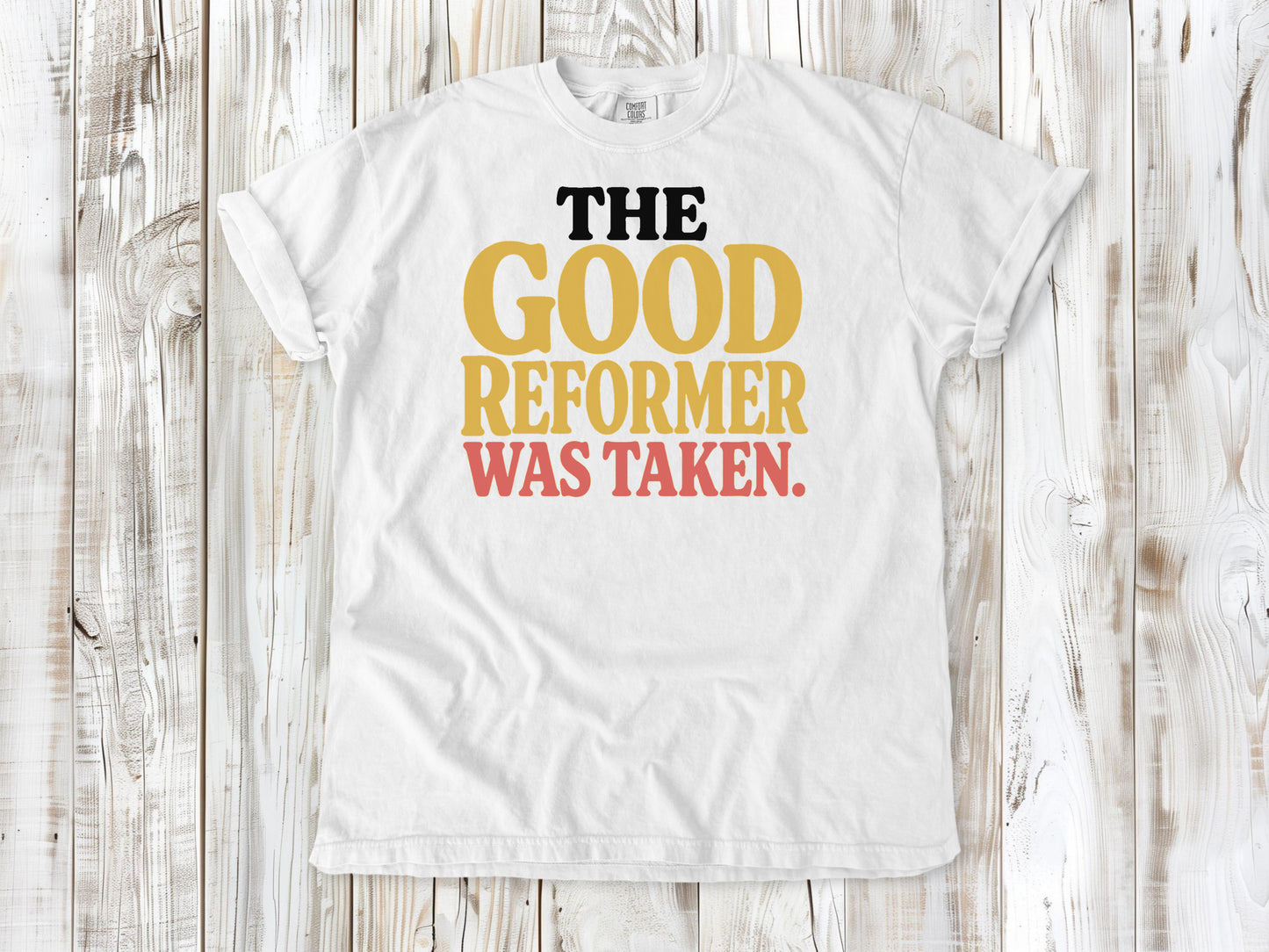 White garment-dyed tee with The Good Reformer Was Taken Pilates studio graphic.