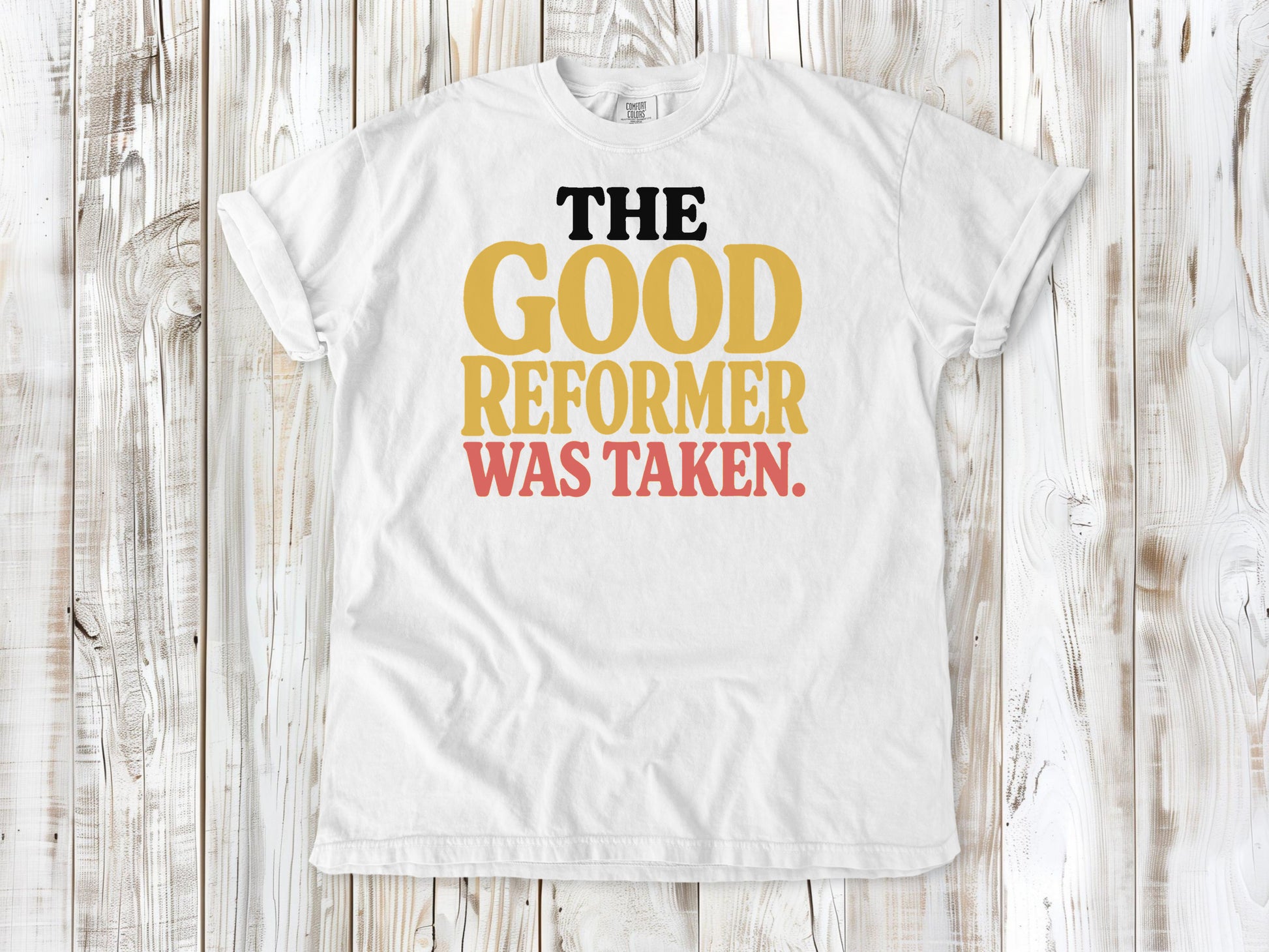 White garment-dyed tee with The Good Reformer Was Taken Pilates studio graphic.