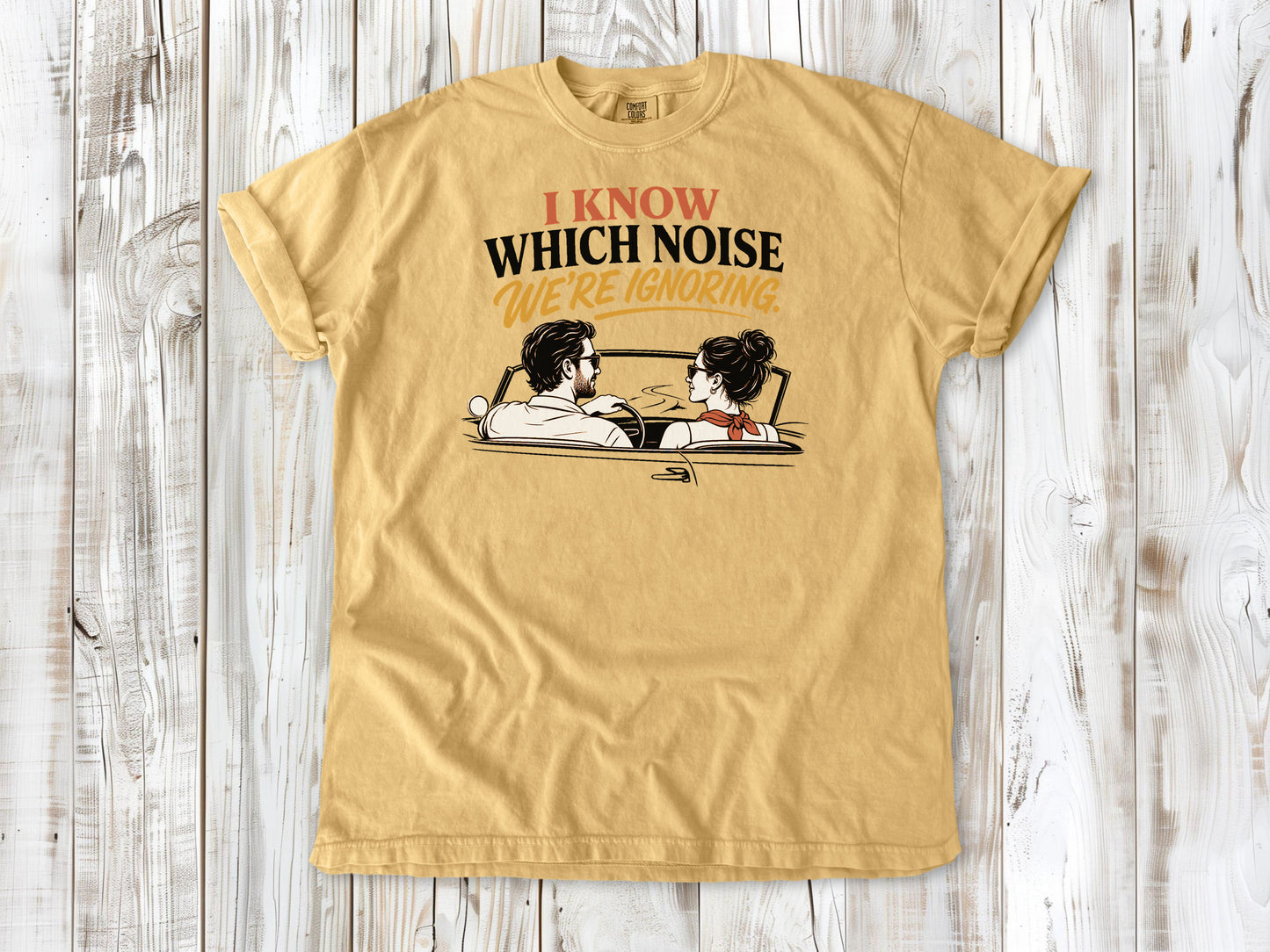 Mustard garment-dyed tee with I Know Which Noise We Are Ignoring car repair graphic.