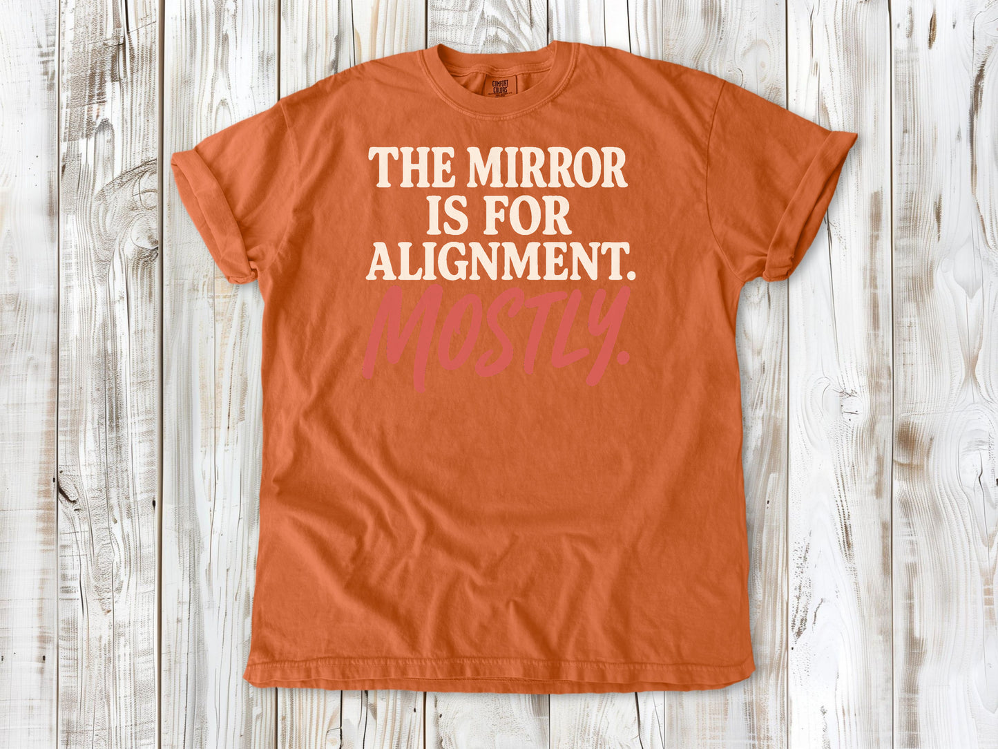 Burnt Orange garment-dyed tee with The Mirror Is for Alignment Mostly Pilates studio graphic.