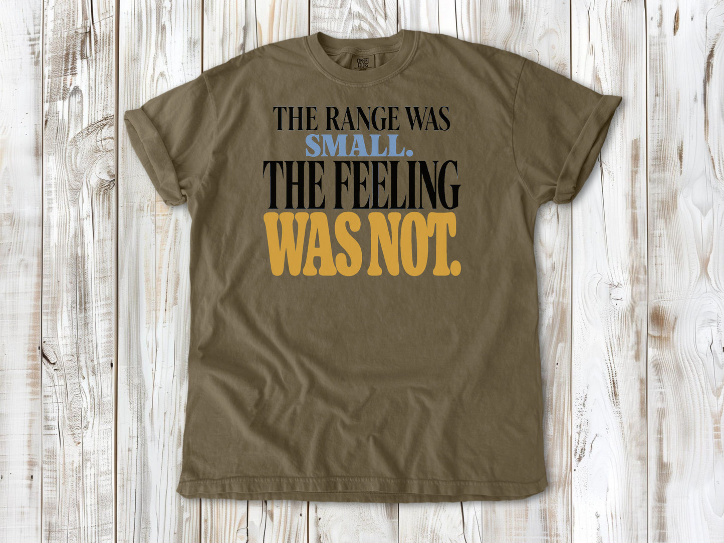 Khaki garment-dyed tee with The Range Was Small The Feeling Was Not Pilates graphic.