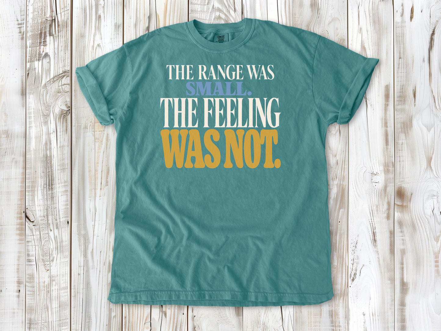 Seafoam garment-dyed tee with The Range Was Small The Feeling Was Not Pilates graphic.