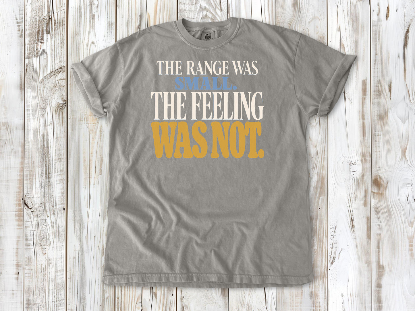 Grey garment-dyed tee with The Range Was Small The Feeling Was Not Pilates graphic.
