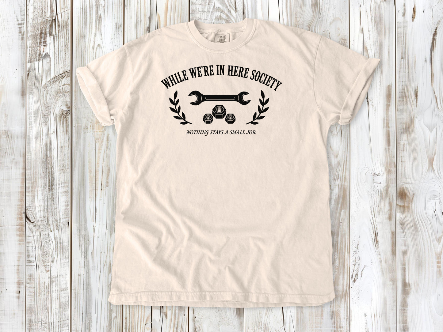 Ivory garment-dyed tee with While We're in Here Society garage humor graphic.