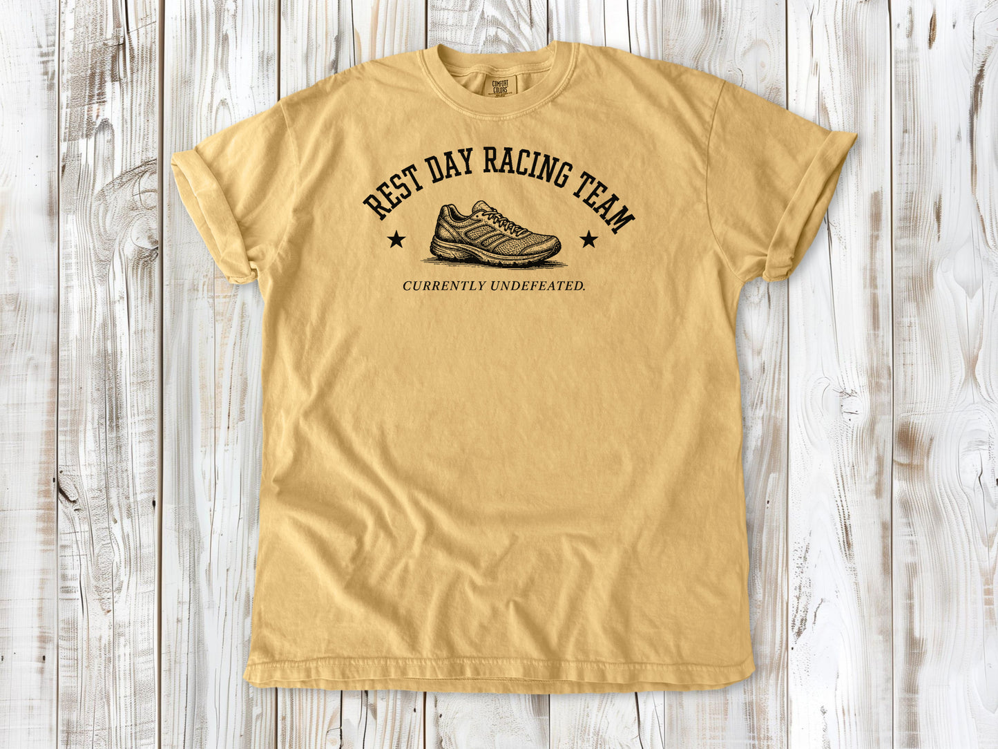 Mustard garment-dyed tee with Rest Day Racing Team running humor graphic.