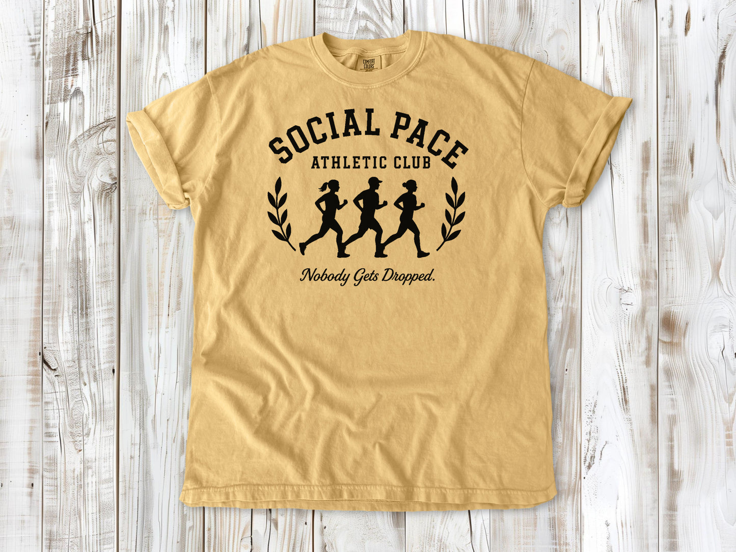 Mustard garment-dyed tee with Social Pace Athletic Club group running graphic.