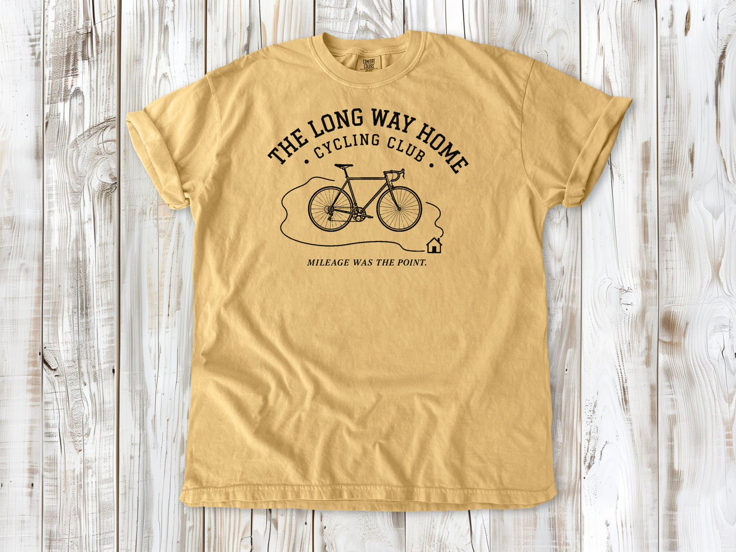 Mustard garment-dyed tee with The Long Way Home Cycling Club bicycle graphic.