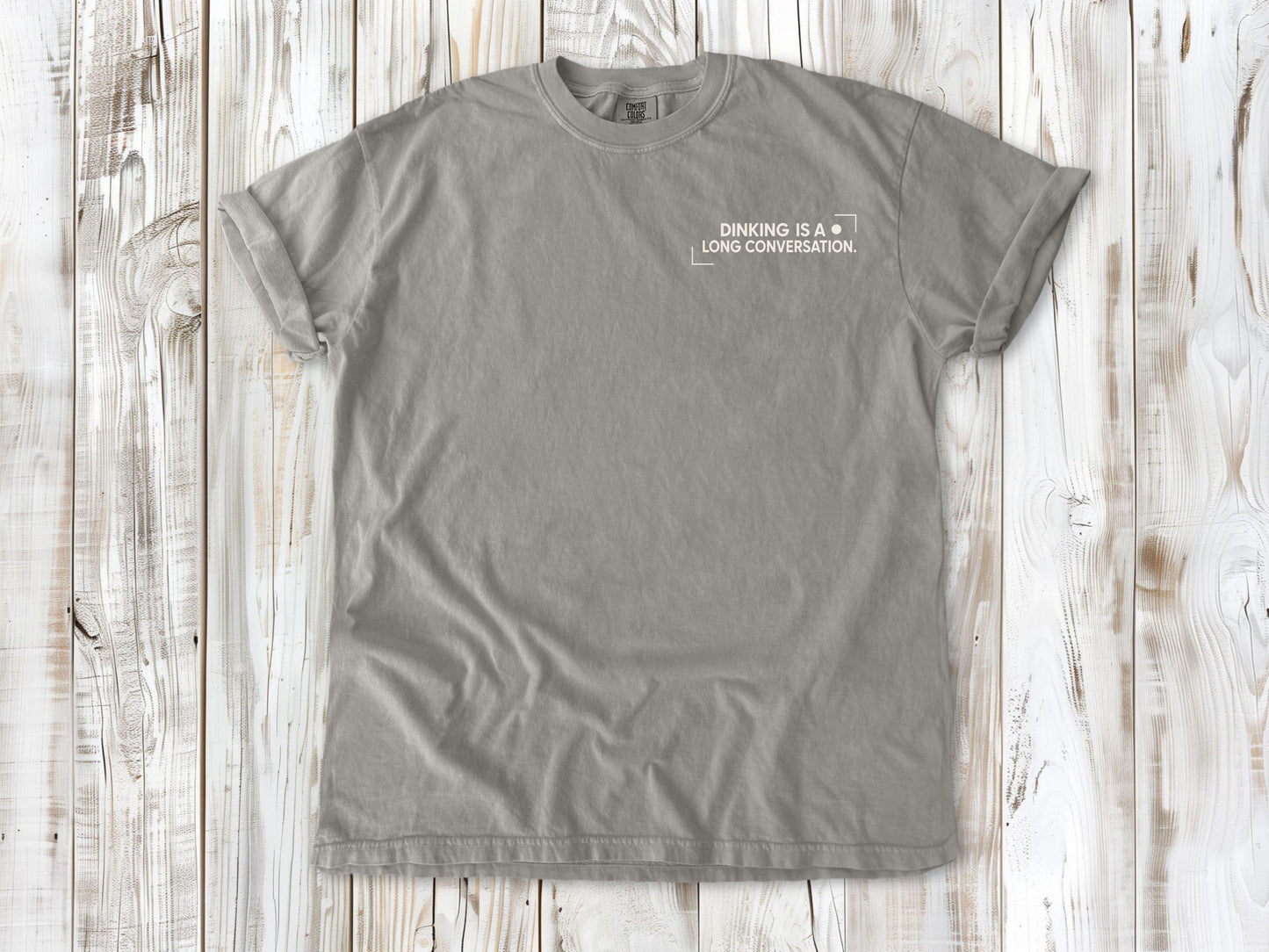 Grey garment-dyed tee with Dinking Is a Long Conversation small left-chest pickleball graphic.