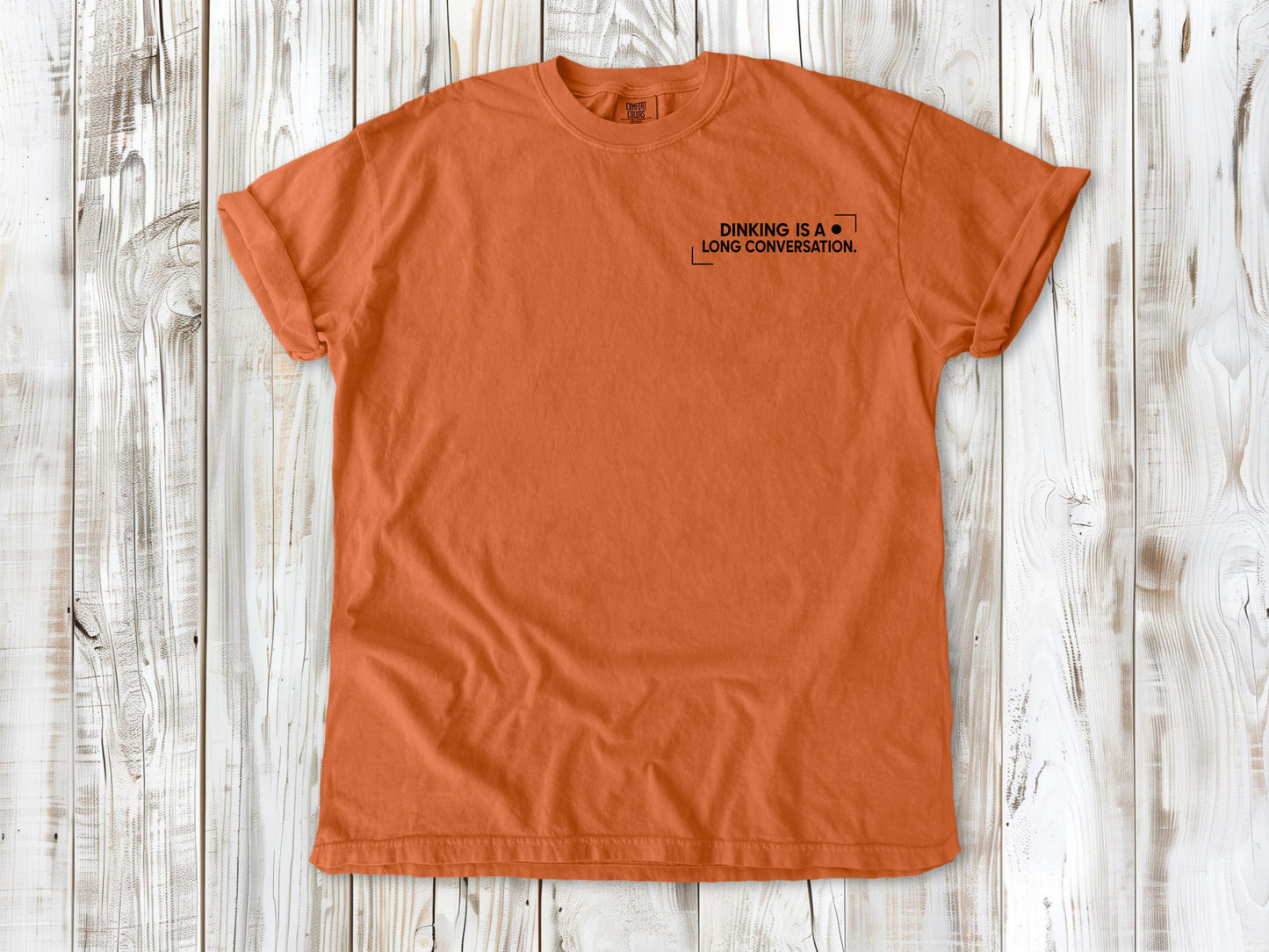 Burnt Orange garment-dyed tee with Dinking Is a Long Conversation small left-chest pickleball graphic.