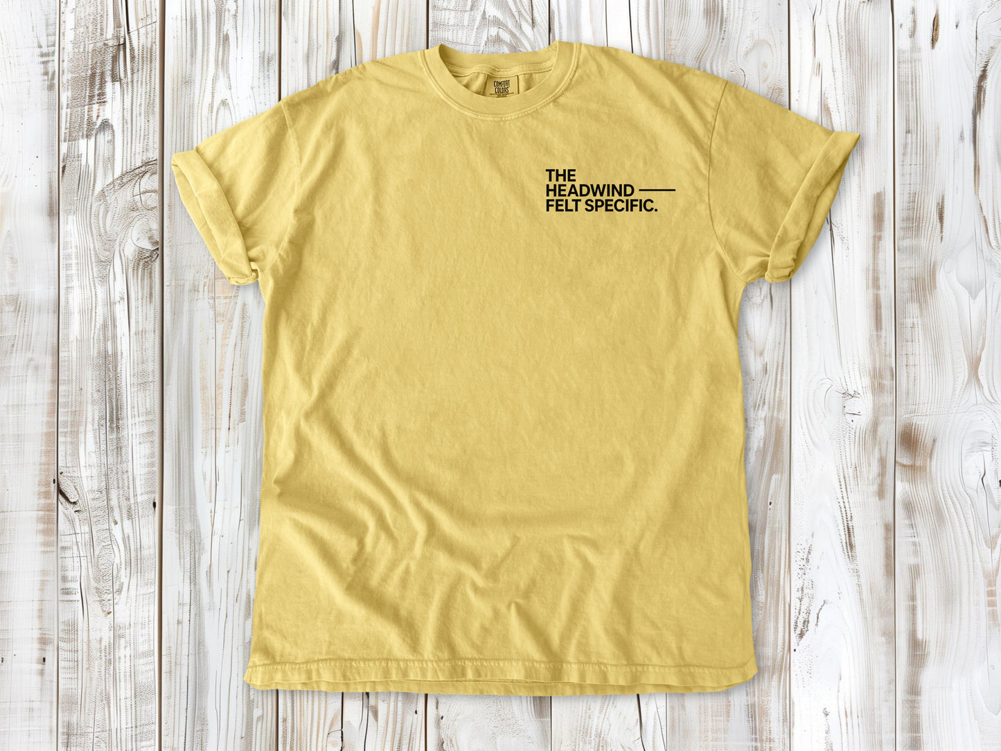 Butter garment-dyed tee with The Headwind Felt Specific small left-chest cycling graphic.