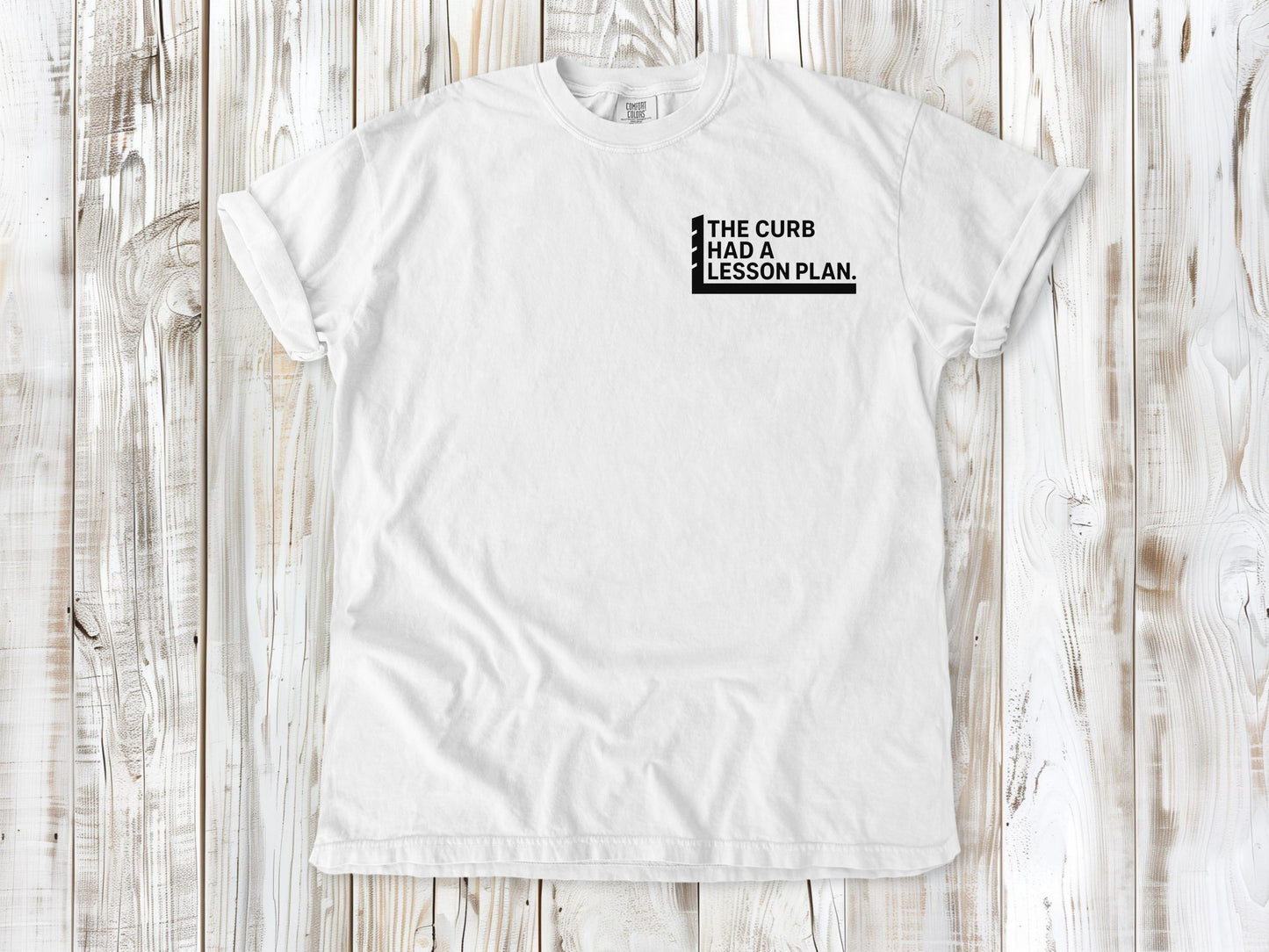 White garment-dyed tee with The Curb Had a Lesson Plan small left-chest skate graphic.
