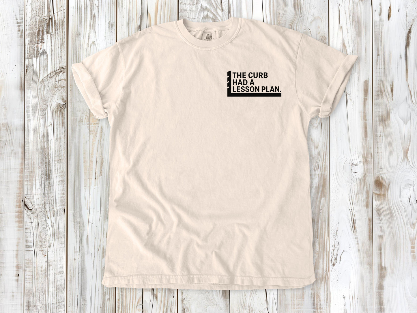 Ivory garment-dyed tee with The Curb Had a Lesson Plan small left-chest skate graphic.
