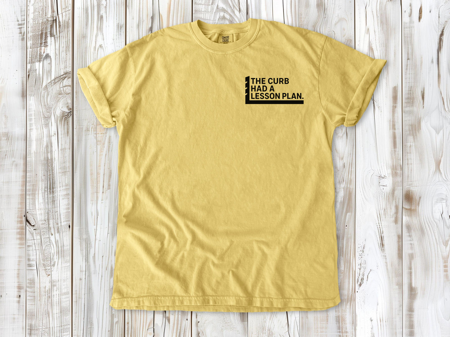 Butter garment-dyed tee with The Curb Had a Lesson Plan small left-chest skate graphic.
