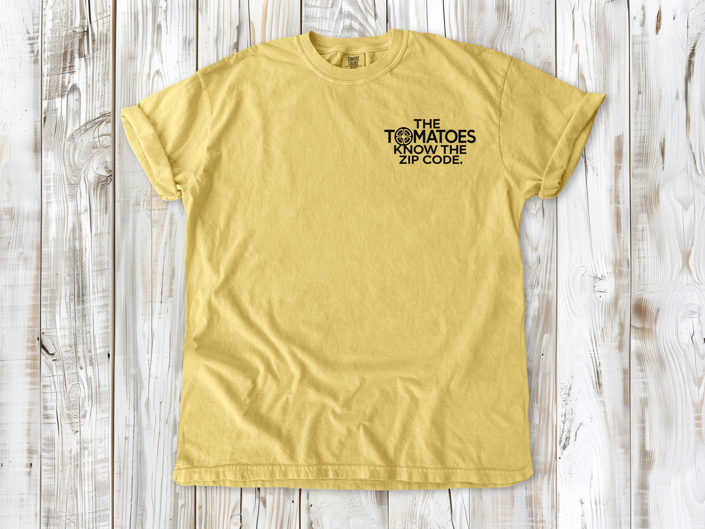 Butter garment-dyed tee with The Tomatoes Know the Zip Code small left-chest gardening graphic.