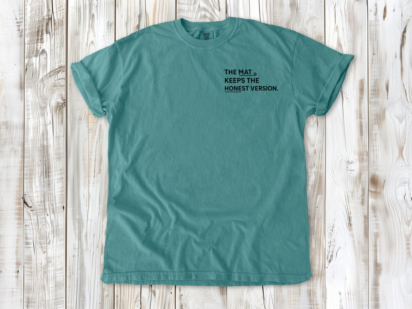 Seafoam garment-dyed tee with The Mat Keeps the Honest Version small left-chest yoga graphic.