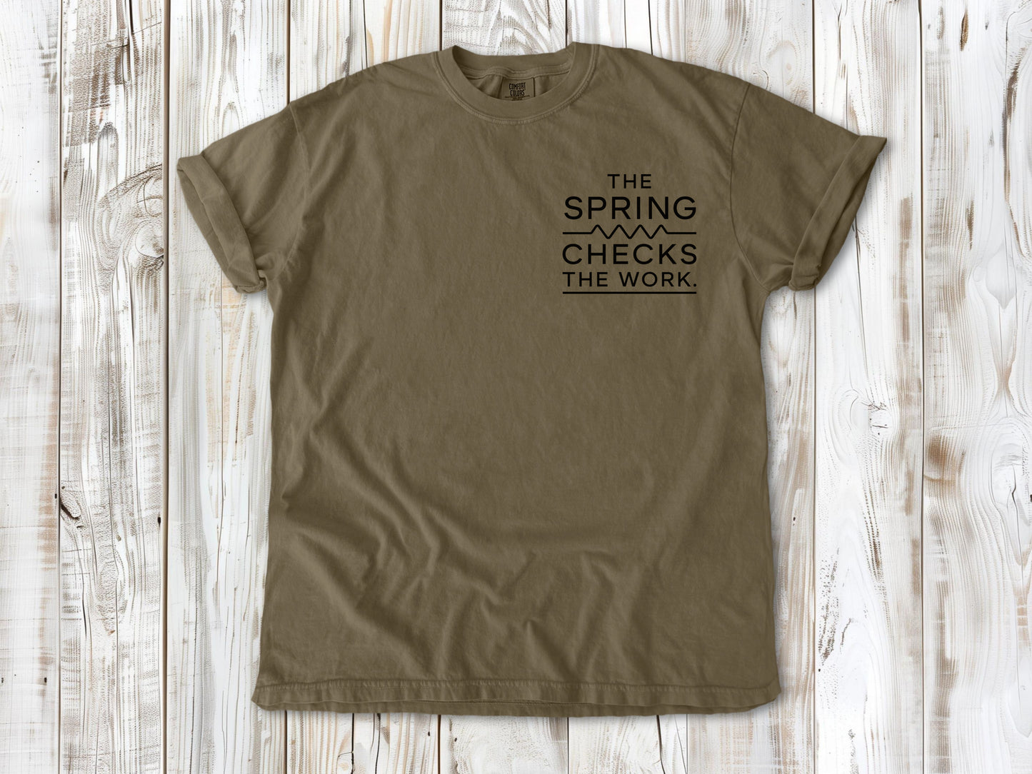 Khaki garment-dyed tee with The Spring Checks the Work small left-chest Pilates graphic.