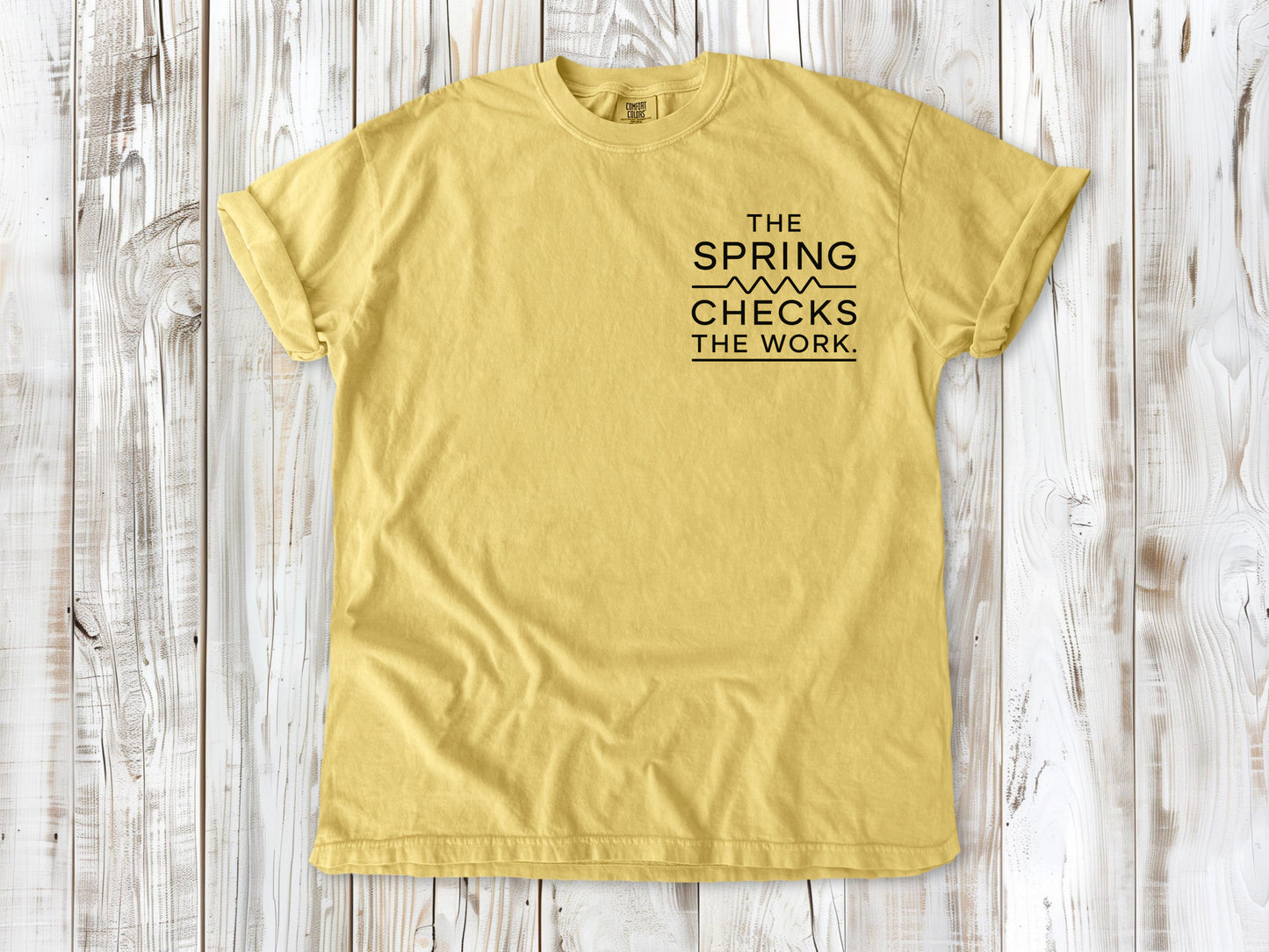 Butter garment-dyed tee with The Spring Checks the Work small left-chest Pilates graphic.