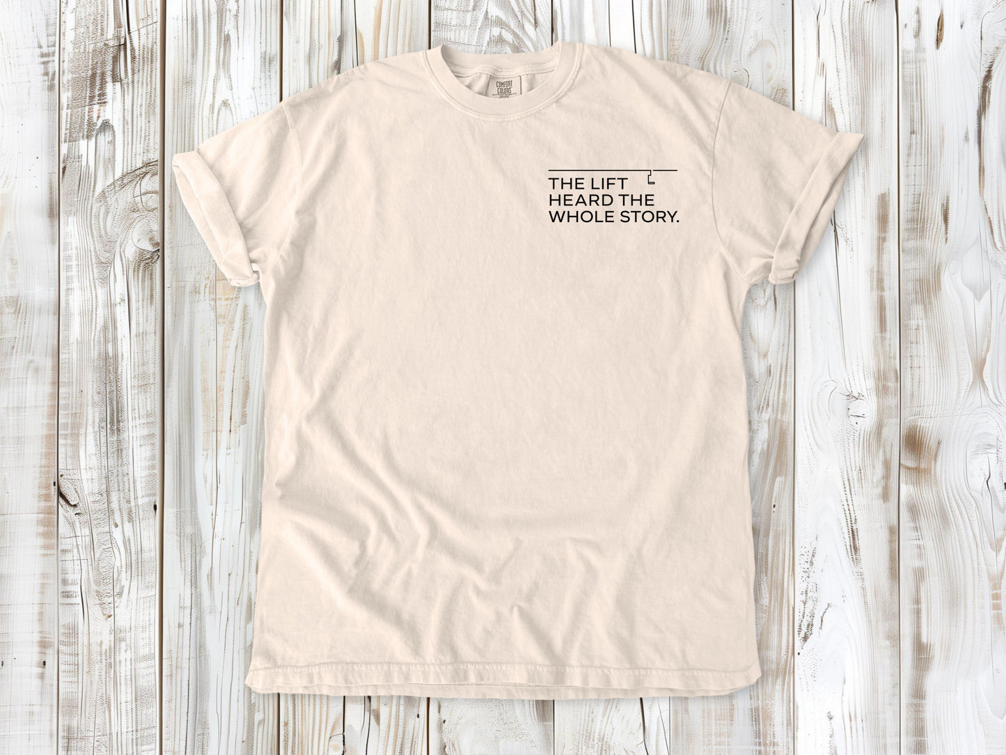 Ivory garment-dyed tee with The Lift Heard the Whole Story small left-chest snowboarding graphic.