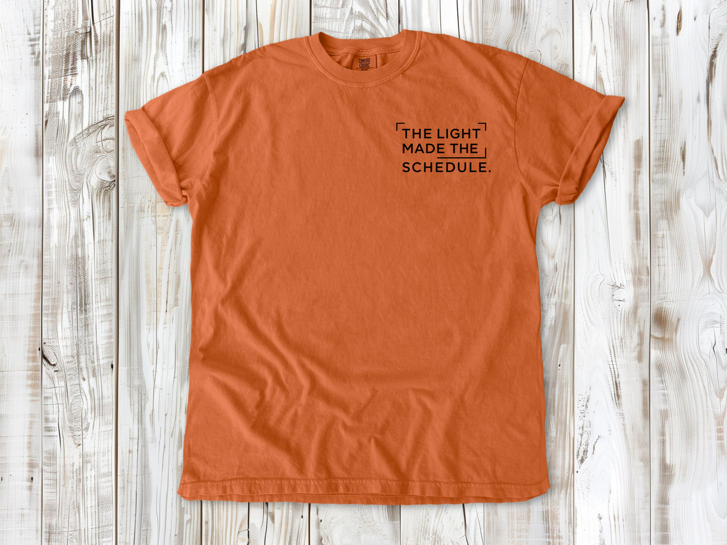 Burnt Orange garment-dyed tee with The Light Made the Schedule small left-chest photography graphic.