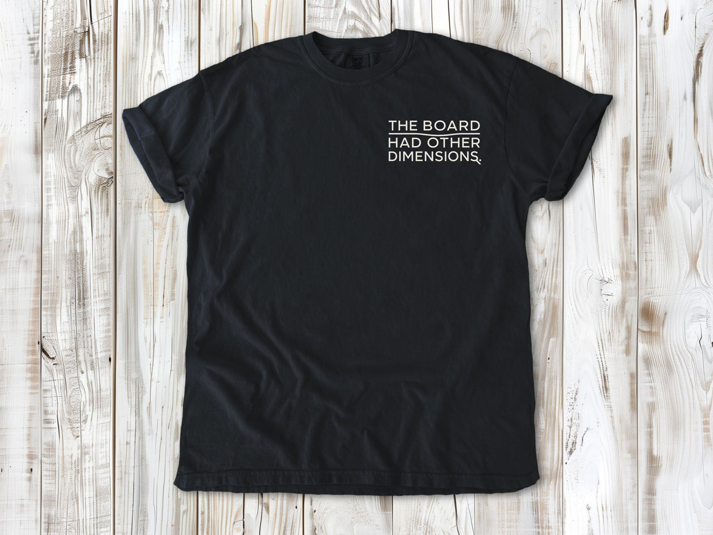 Graphite garment-dyed tee with The Board Had Other Dimensions small left-chest woodworking graphic.
