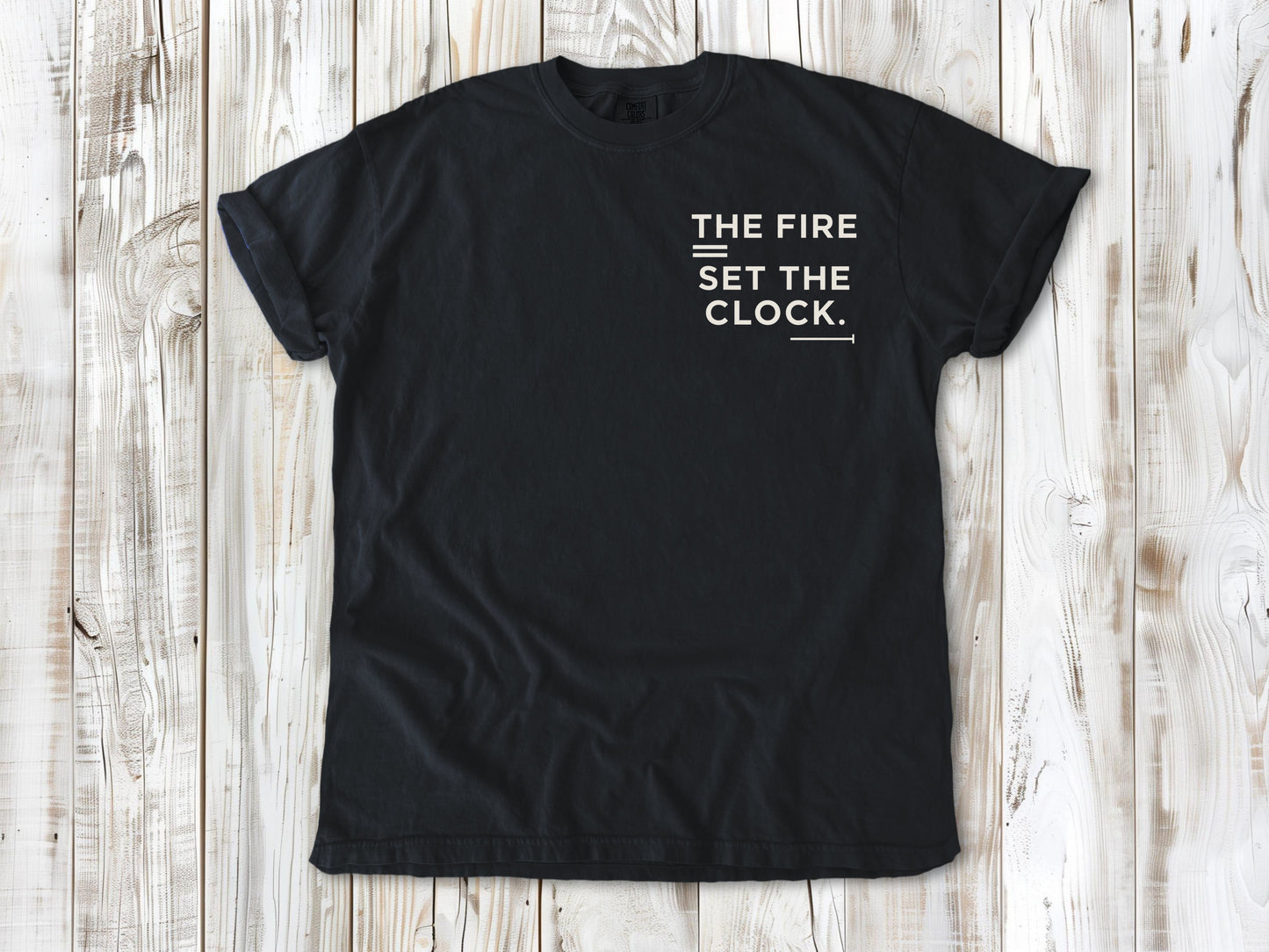Graphite garment-dyed tee with The Fire Set the Clock small left-chest camping graphic.