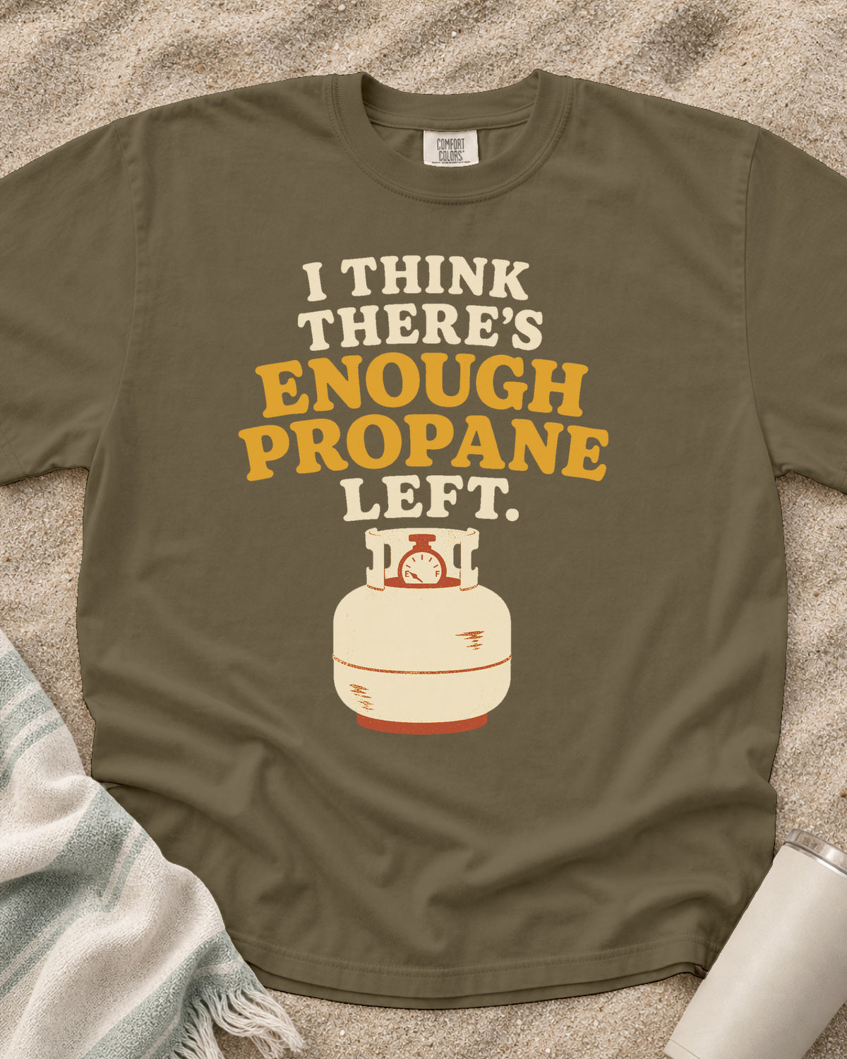 Khaki garment-dyed tee with I Think There’s Enough Propane Left griddle graphic.