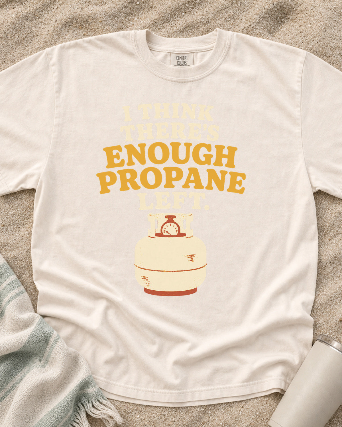 Ivory garment-dyed tee with I Think There’s Enough Propane Left griddle graphic.