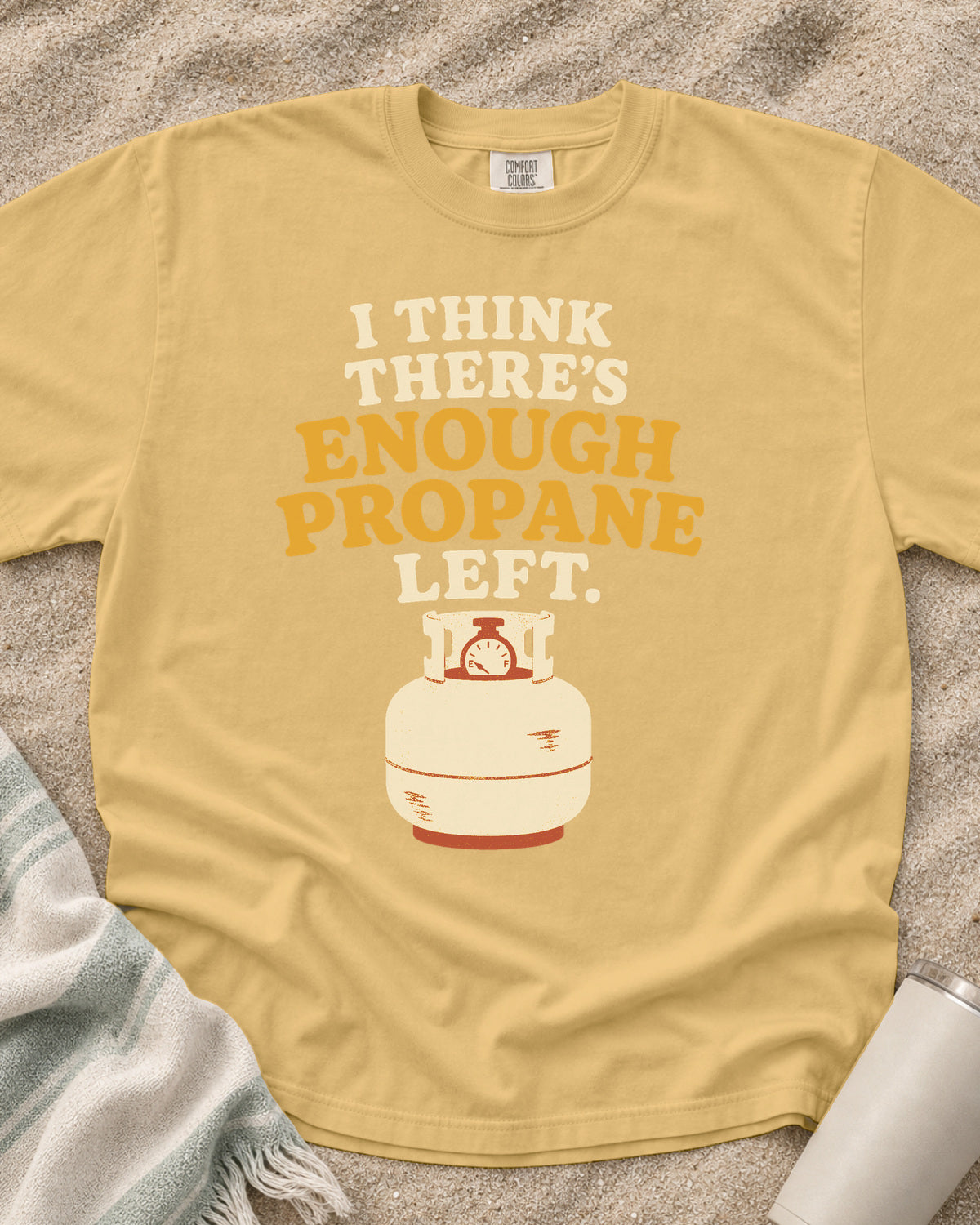Mustard garment-dyed tee with I Think There’s Enough Propane Left griddle graphic.