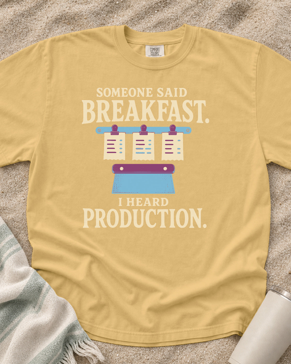 Mustard garment-dyed tee with Someone Said Breakfast I Heard Production graphic.