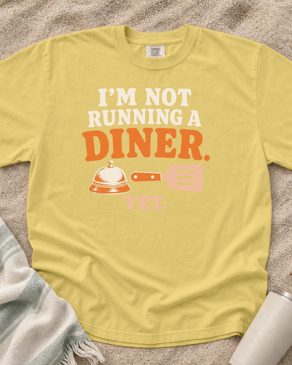 Butter garment-dyed tee with I’m Not Running a Diner Yet griddle graphic.