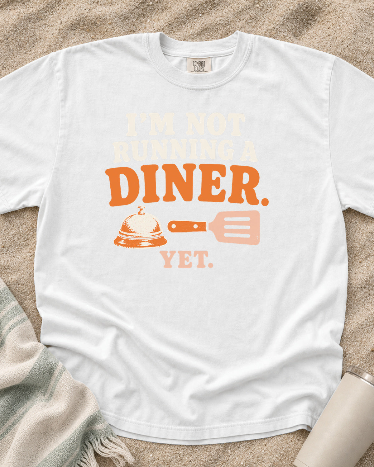 White garment-dyed tee with I’m Not Running a Diner Yet griddle graphic.