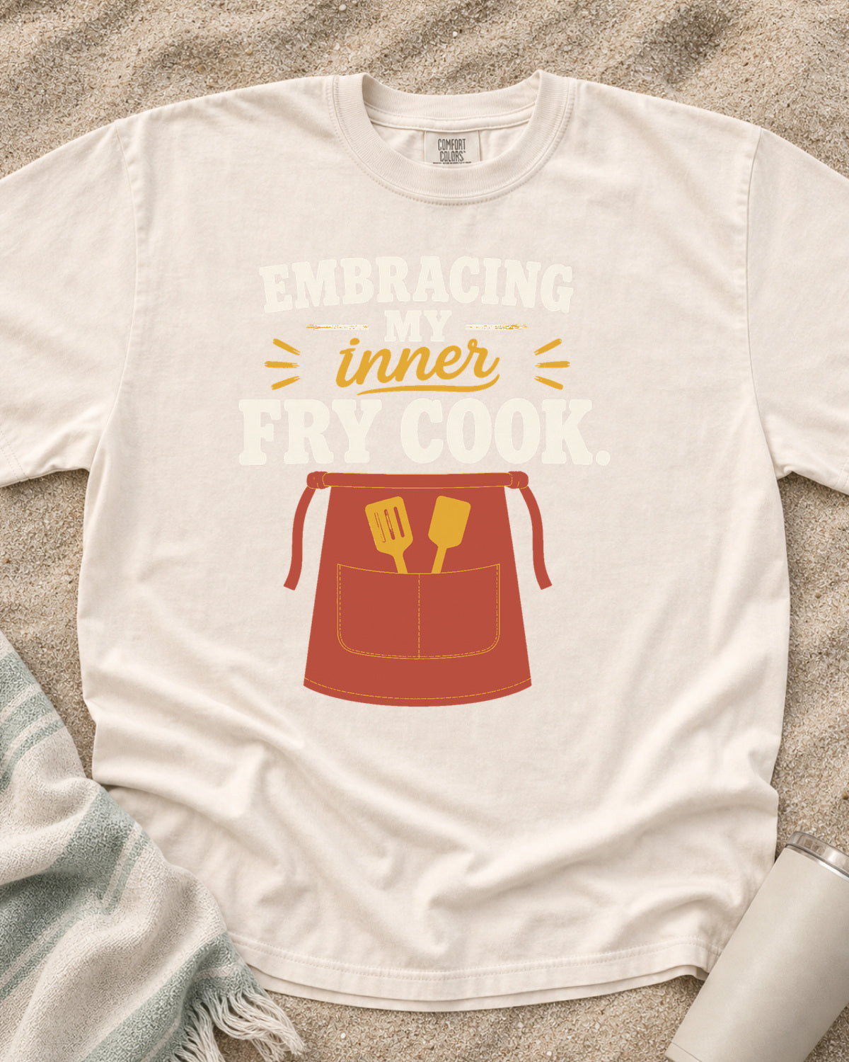 Ivory garment-dyed tee with Embracing My Inner Fry Cook griddle graphic.