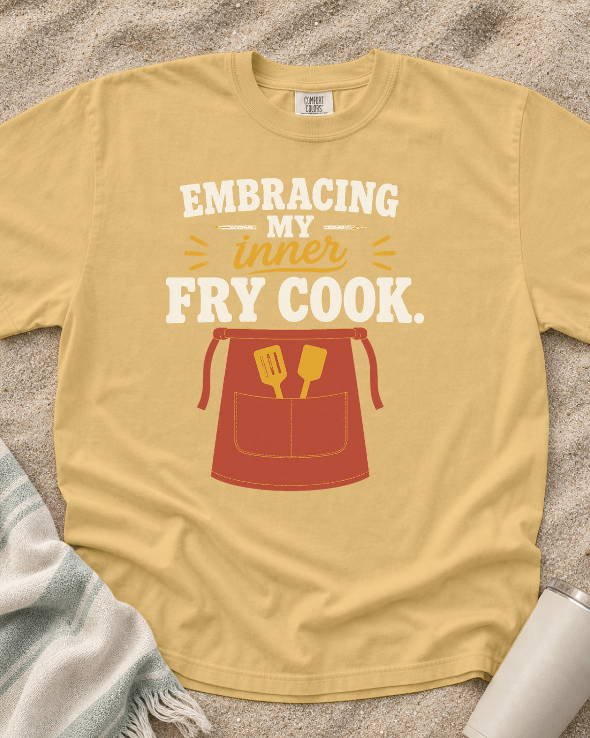 Mustard garment-dyed tee with Embracing My Inner Fry Cook griddle graphic.