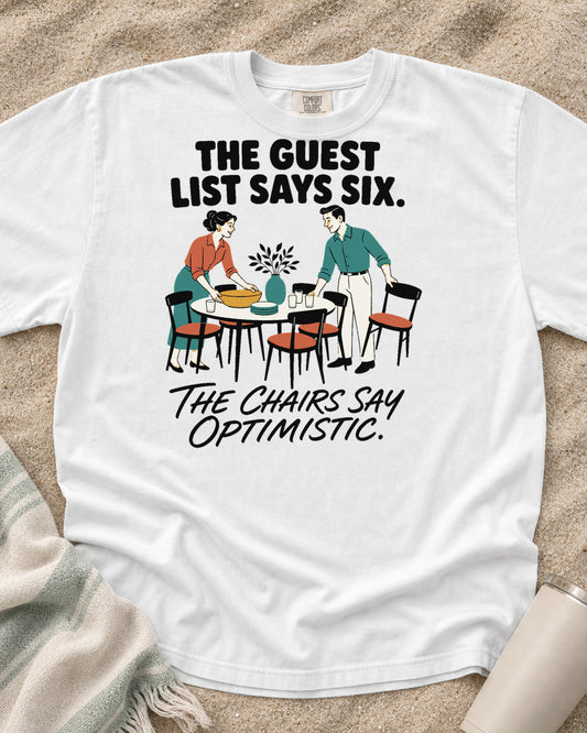 White Comfort Colors 1717 tee with The Guest List Says Six. The Chairs Say Optimistic graphic.