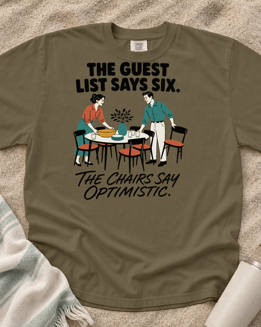 Khaki Comfort Colors 1717 tee with The Guest List Says Six. The Chairs Say Optimistic graphic.